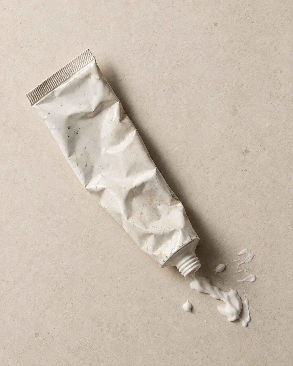 Een uitgeknepen tube ontharingscrème zonder dop, met wat gemorste crème
